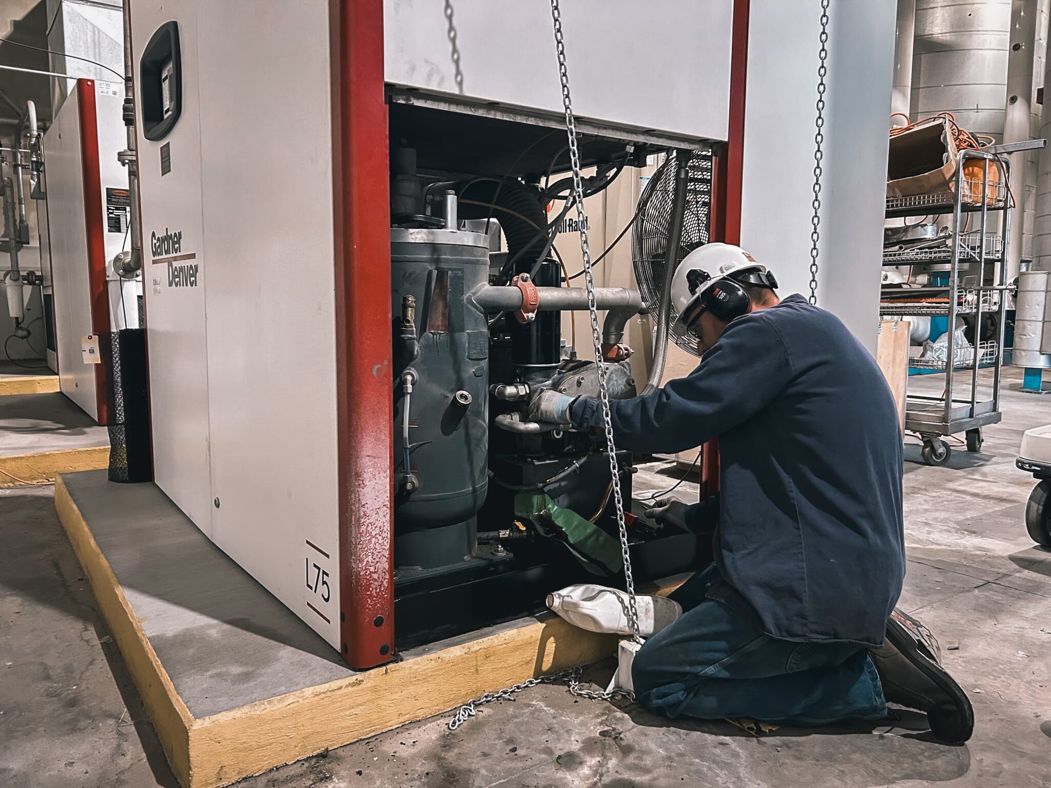 Rasmussen Mechanical’s team services Gardner Denver and other major air compressor systems across the Midwest. Alt text: Rasmussen Mechanical technician performing industrial air compressor maintenance on a Gardner Denver unit.